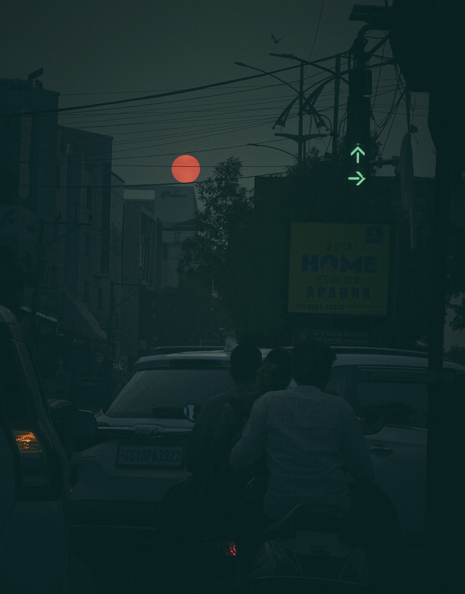 Moody urban night scene with red sun/moon through power lines and green directional arrow - urban night photography
