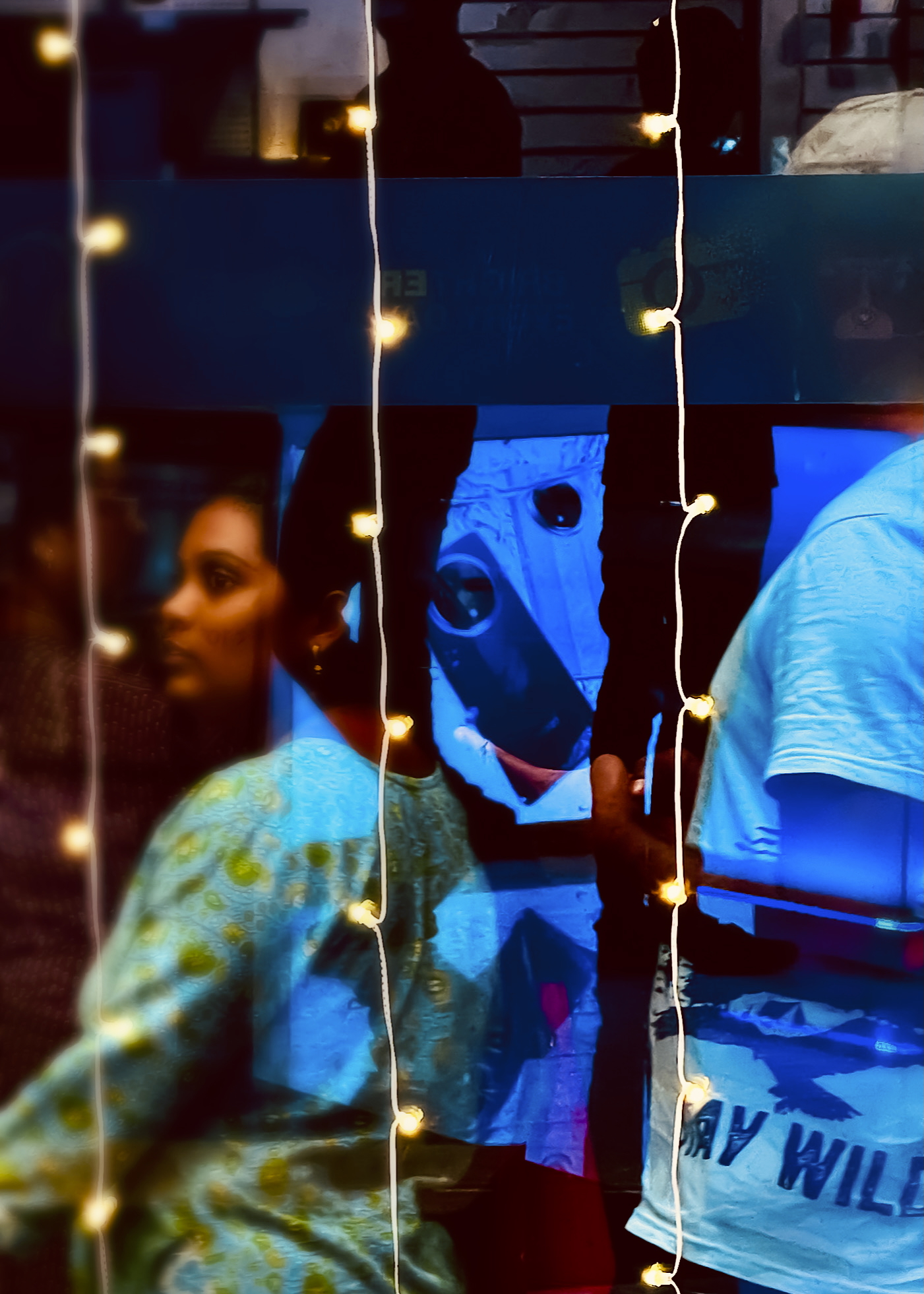 Complex layered reflections in glass with string lights and multiple figures - urban reflection photography