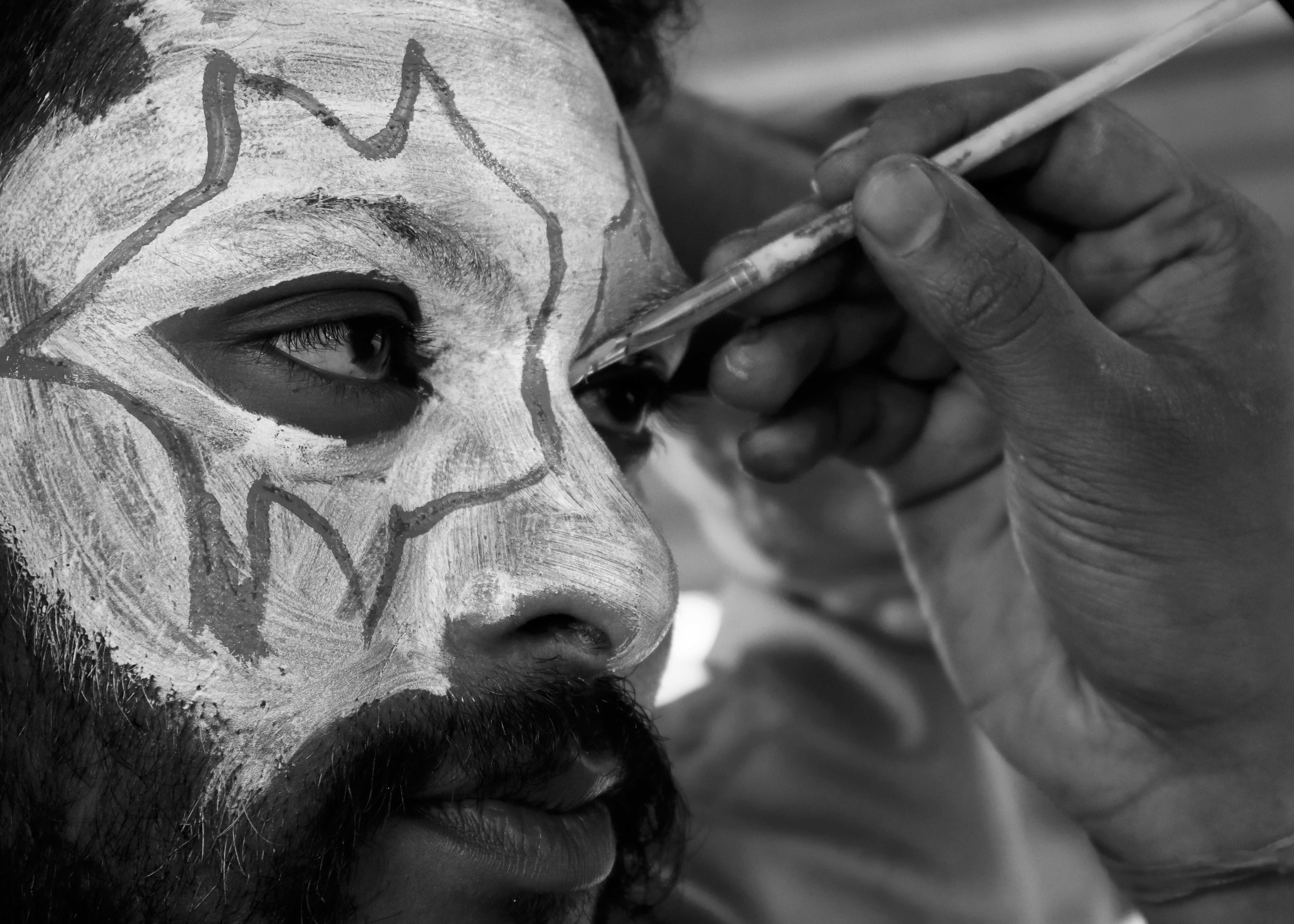Black and white portrait with traditional face paint showing intricate eye patterns and cultural designs - Faces we don't forget photography series by Shital Morjaria