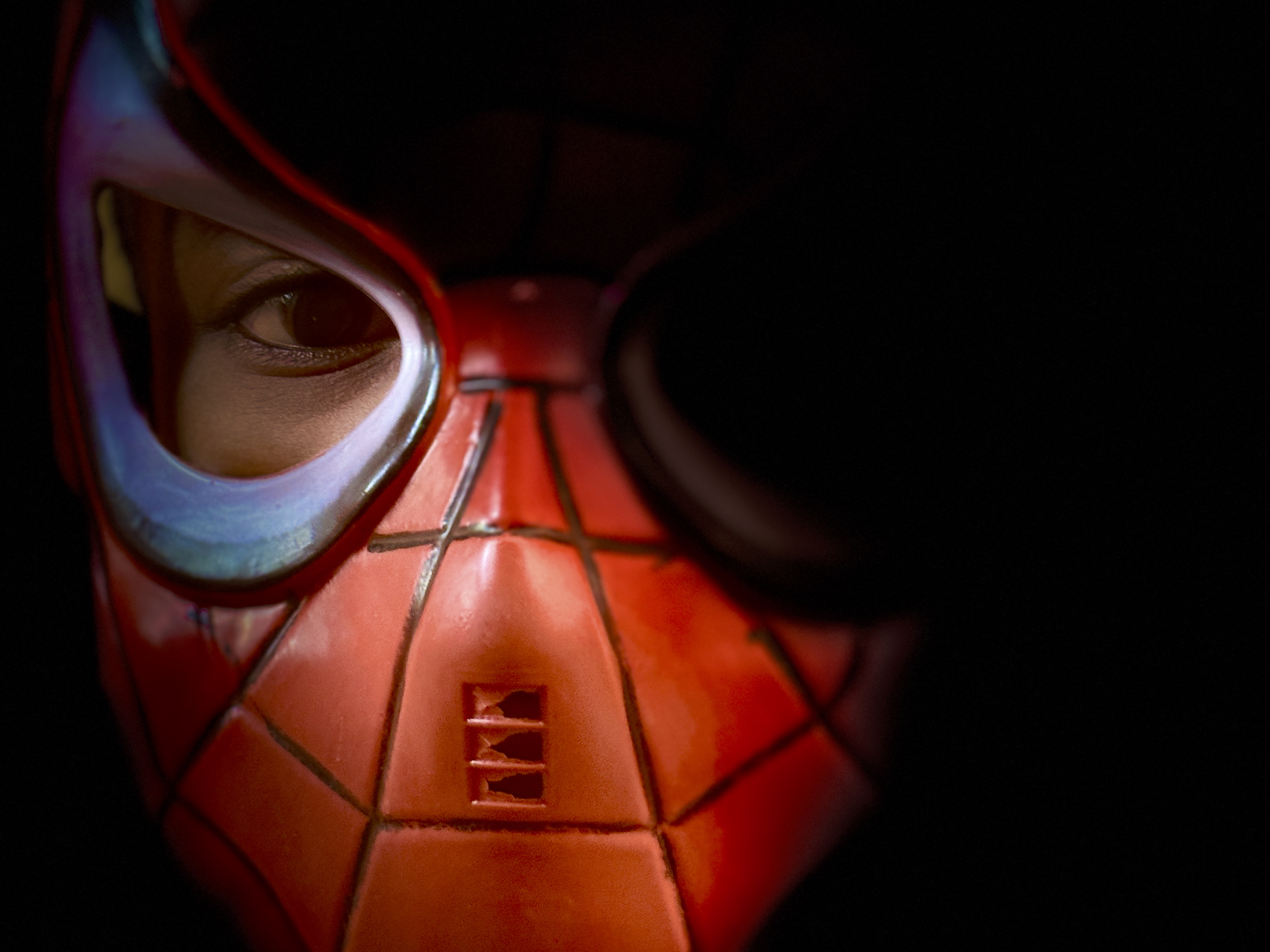 Close-up portrait showing person wearing red mask with visible eye - dramatic portrait photography