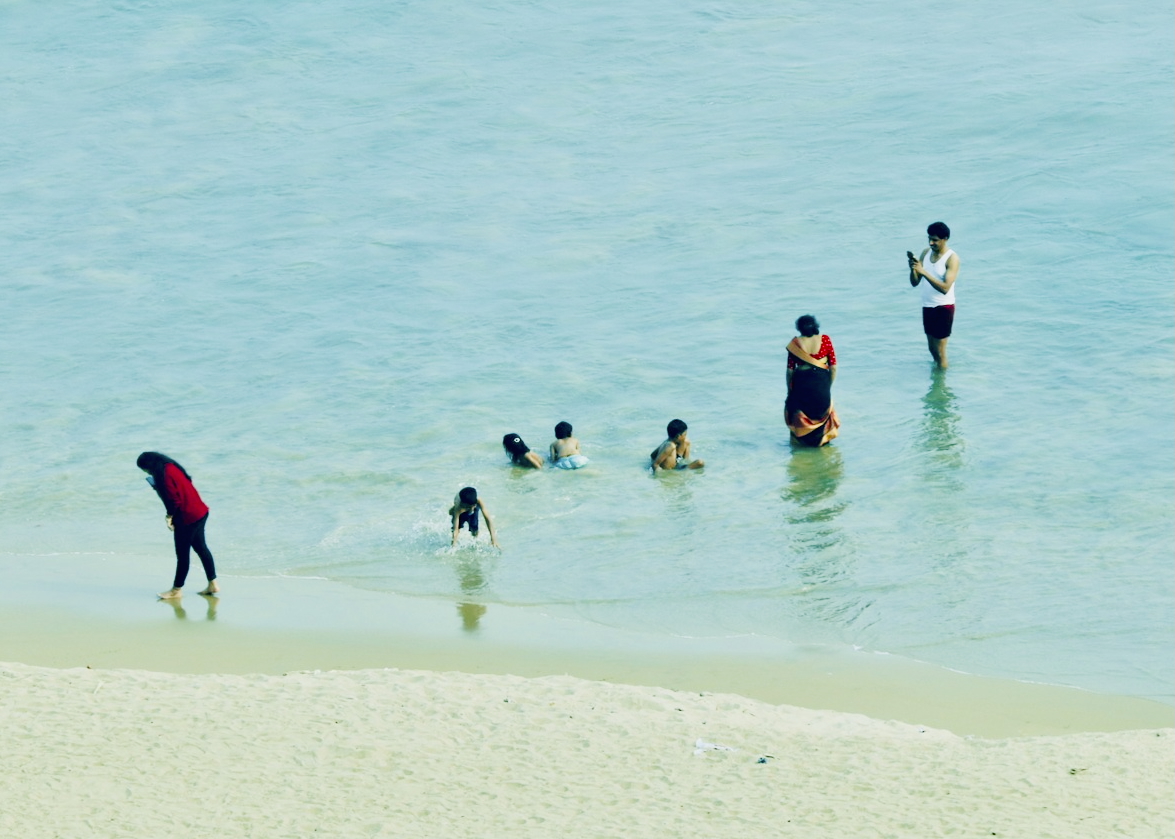 People enjoying turquoise ocean water in family beach scene - joyful coastal life photography