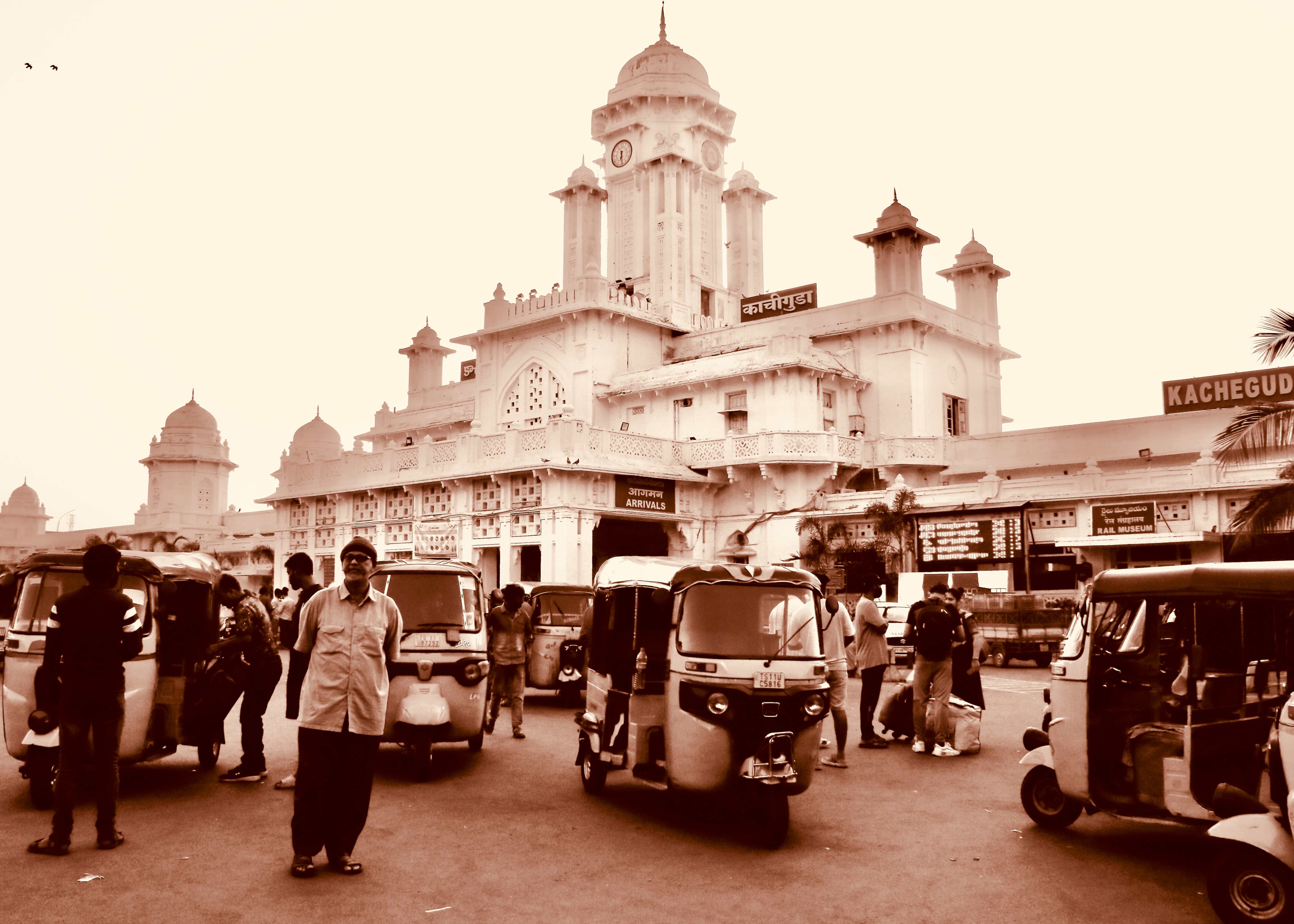 Sepia-toned busy street scene with auto-rickshaws and people before Indo-Islamic railway station - Hyderabad street photography