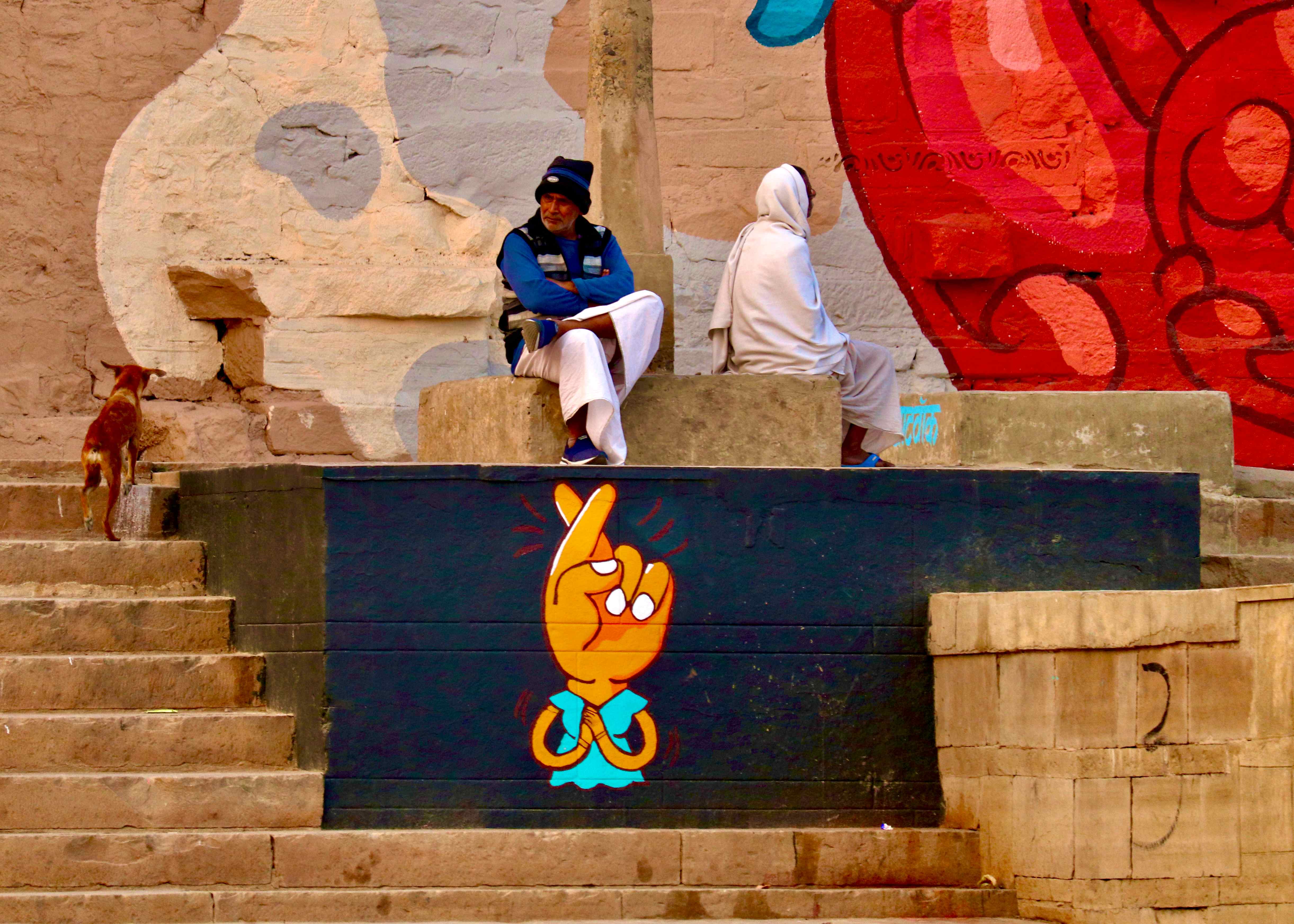 Colorful street art scene with people sitting on steps near vibrant murals - urban culture and street life photography